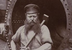 vintage blue-collar employee with large sledgehammer long beard
